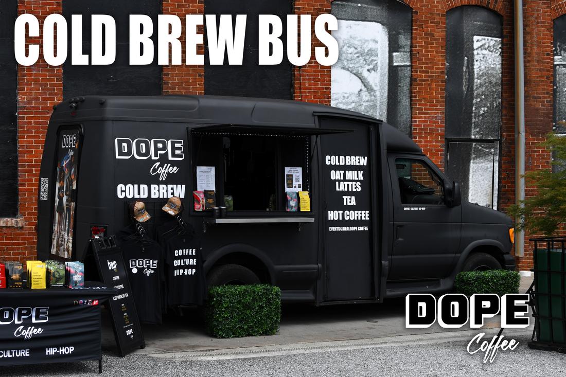 The Dope Coffee Cold Brew Bus parked on a brick street with a merch table out front