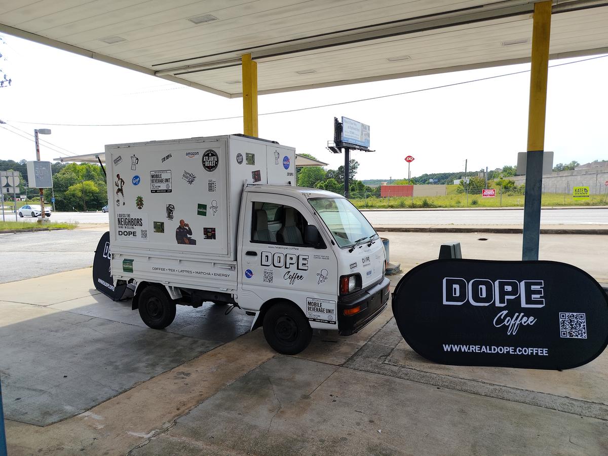 The Dope Coffee mini truck under a gas-station canopy next to a Dope pop-up sign