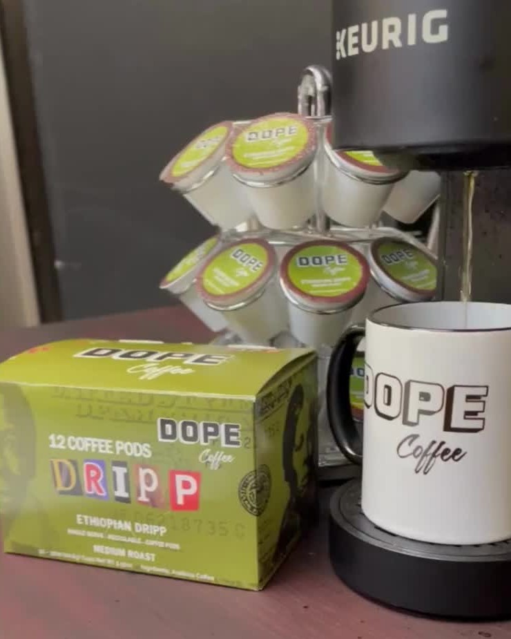 A Keurig pours into a DOPE mug beside a box of Ethiopian Dripp pods